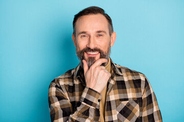 Photo portrait of aged man thoughtful smiling touching chin isolated on bright blue color background