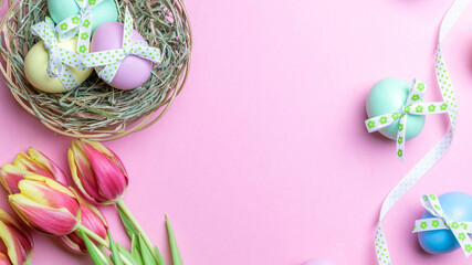 Fototapeta na wymiar Easter Colorful egg with tape ribbon, spring tulips, white feathers on pastel pink background in Happy Easter decoration. Spring holiday flat lay concept.