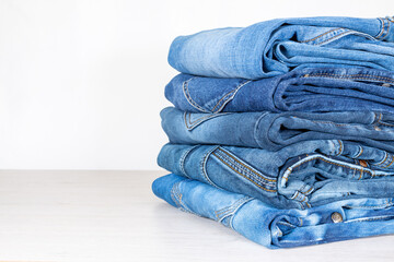 Denim trousers folded in a pile on a store window.