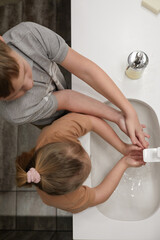 Top down view at brother and sister washing hands together while standing by sink at home, child with down syndrome, copy space