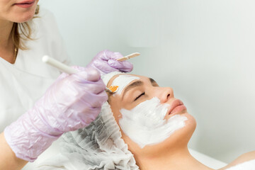 Facial skin care and protection. A young woman at a beauticians appointment. The specialist applies a cream mask to the face