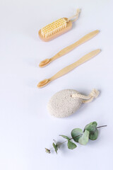 Toiletries on white background. Pumice stone, tothbrushes and body brush, eucalyptus leaves. Top view