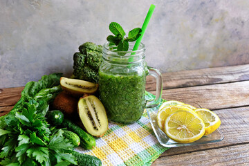 Green home-made smoothies in a glass jar on a wooden table on a checkered napkin. ingredients-lemon, spinach, kiwi, broccoli.