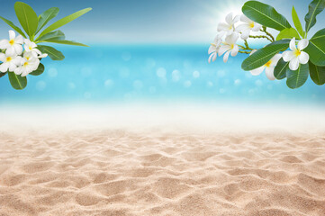 Focus area at sandy beach  and bokeh sun light on blurry sea with plumeria flower branch Tropical Summer time concept background