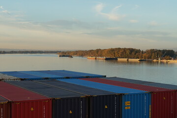 River barges and tug boats moored near container terminal on the Columbia river surrounded by trees...