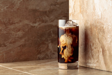 Iced coffee with cream on a beige ceramic table.