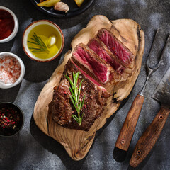 New York Striploin . Sliced grilled meat steak with sauce on wooden board on grey background. Top view - 421187076