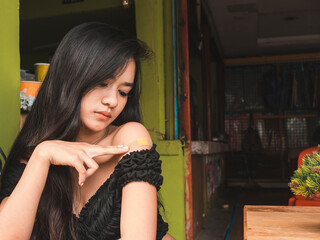 A cute asian girl checks and worries over a covered sore that is throbbing with some pain. Possible...