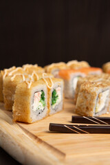 Big sushi set on light wooden dish isolated on black background