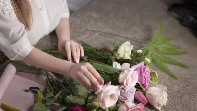 In the frame, female hands with a good manicure, and flowers for a bouquet.
