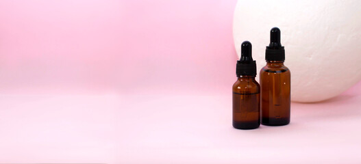 Natural essential oil, in a glass bottle with a pipette on a pink background. Alternative medicine, an aromatic cosmetic product for skin care. Layout of skin care products. Copy space.