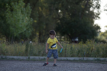 Fototapeta premium a boy in a yellow T-shirt, shorts, rubber shoes plays with his toy phone