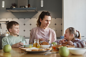 Portrait of mother looking at girl with down syndrome while sitting at dining table and enjoying...