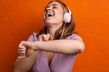 Joyful woman dancing while listening music with headphones