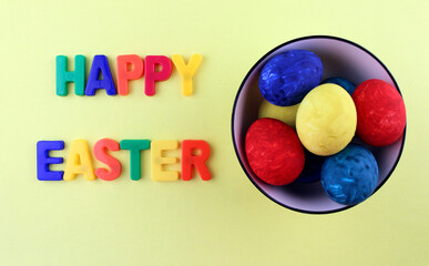 Fototapeta na wymiar Painted colorful eggs in a white plate with the inscription 