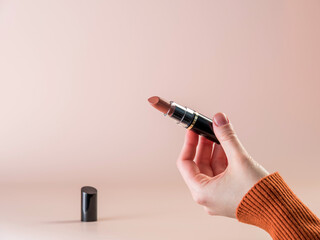 Close-up of a girl's hand with lipstick. Powdery background