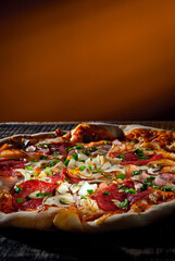 Round pizza on a wooden board. Pizza on orange background close up. Copy space and free space for...