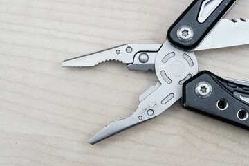 Selective focus of combination pliers on top light wooded color background. 
