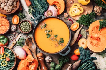  Pumpkin soup with vegetarian cooking ingredients, wooden spoons, kitchen utensils on wooden background. Top view. Vegan diet. Autumn harvest. Healthy, clean food and eating concept. Zero waste © jchizhe
