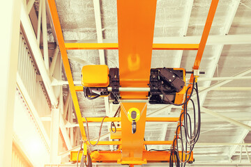 Overhead crane inside factory or warehouse. That industrial machinery or lifting equipment consist of hoist, hook and wire rope traveling on beam girder structure. For manufacturing production plant. - obrazy, fototapety, plakaty