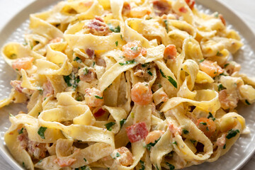 Homemade Garlic Shrimp Bacon Alfredo on a plate on a white wooden table, low angle view. Close-up.