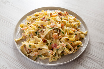 Homemade Garlic Shrimp Bacon Alfredo on a plate on a white wooden table, low angle view.
