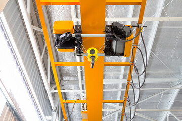 Overhead crane inside factory or warehouse. That industrial machinery or lifting equipment consist of hoist, hook and wire rope traveling on beam girder structure. For manufacturing production plant. - obrazy, fototapety, plakaty