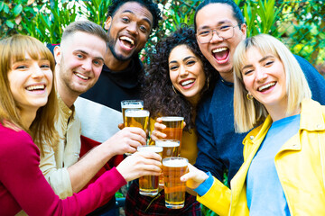 Group of multicultural friends drinking and toasting beer at brewery bar restaurant - Happy people having fun at rooftop home party - Vivid color filter