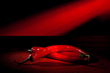 Hot peppers close up. Chilean pepper on a wooden board. Vegetables on a red background. Contrasting...