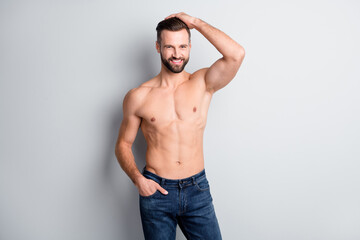 Fototapeta premium Portrait of attractive cheerful well-groomed content guy posing showing biceps isolated over light grey color background