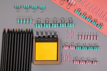 Office supplies. Pencils, paper clips and notepad on a gray and pink background