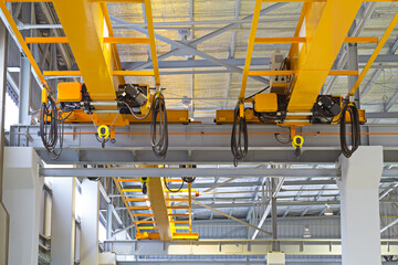 Overhead crane inside factory or warehouse. That industrial machinery or lifting equipment consist of hoist, hook and wire rope traveling on beam girder structure. For manufacturing production plant.