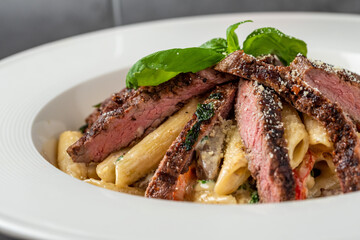 With sliced ​​grilled meat on a creamy penne pasta.