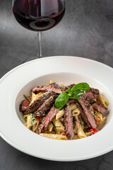 With sliced ​​grilled meat on a creamy penne pasta.