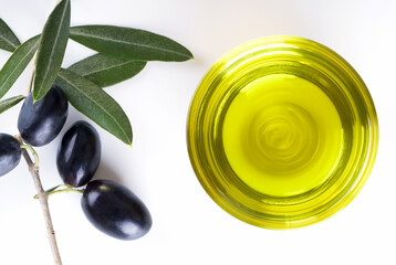 Bowl of glass full of Extra Virgin Olive Oil made in Puglia, Salento on a white table with olive branch. Tipical ingredients of mediterranean diet, healhty eating concept