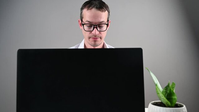 Young man in glasses works at the computer, high quality video