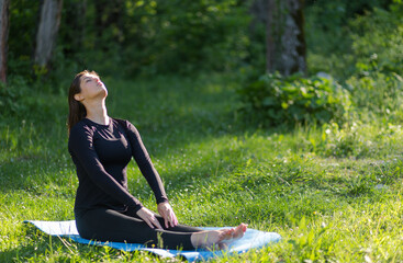 Young woman practicing yoga on mat in a park