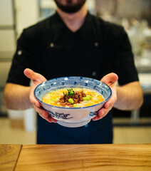 Man holding a bowl of japanese ramen tantanmen soup