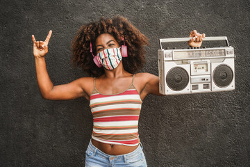 Young african woman listening music with boombox vintage stereo - Focus on face