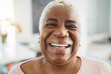 Portrait of happy senior african woman looking at camera indoors at home - Focus on face