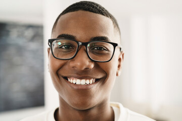 Happy young african man looking at camera indoors at home - Focus on face