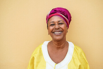 Happy senior african woman wearing traditional dress looking at camera - Focus on face