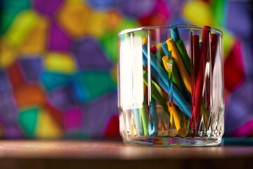 Glass glass with colorful wooden sticks. Coloured background