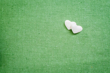 hearts made of refined white sugar lie on green linen fabric