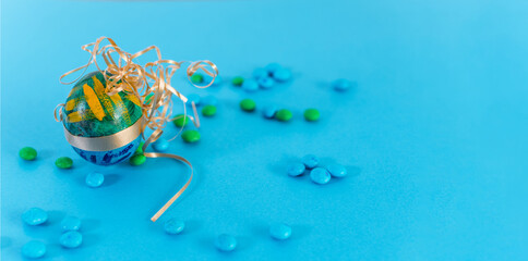 Green and blue Easter egg and candies on a light blue background.