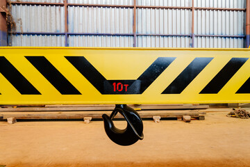Crane hook on a yellow metal girder. Carrying capacity ten tons. Lifting a load weighing ten tons....