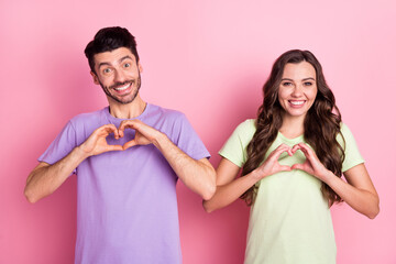 Portrait of attractive funky cheerful couple showing heart symbol amour isolated over pink pastel color background