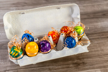 Cute and funny easter eggs in a egg box on wooden background.