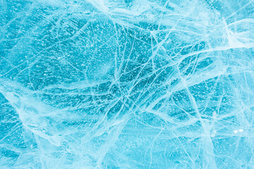 Texture of beautiful blue ice with cracks and air bubbles in the frozen lake. Winter nature background. Lake Baikal, Siberia, Russia.