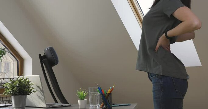Working from home and exercise at home office. Beautiful woman stretching her back while sitting at workplace. Healthy living and body care.